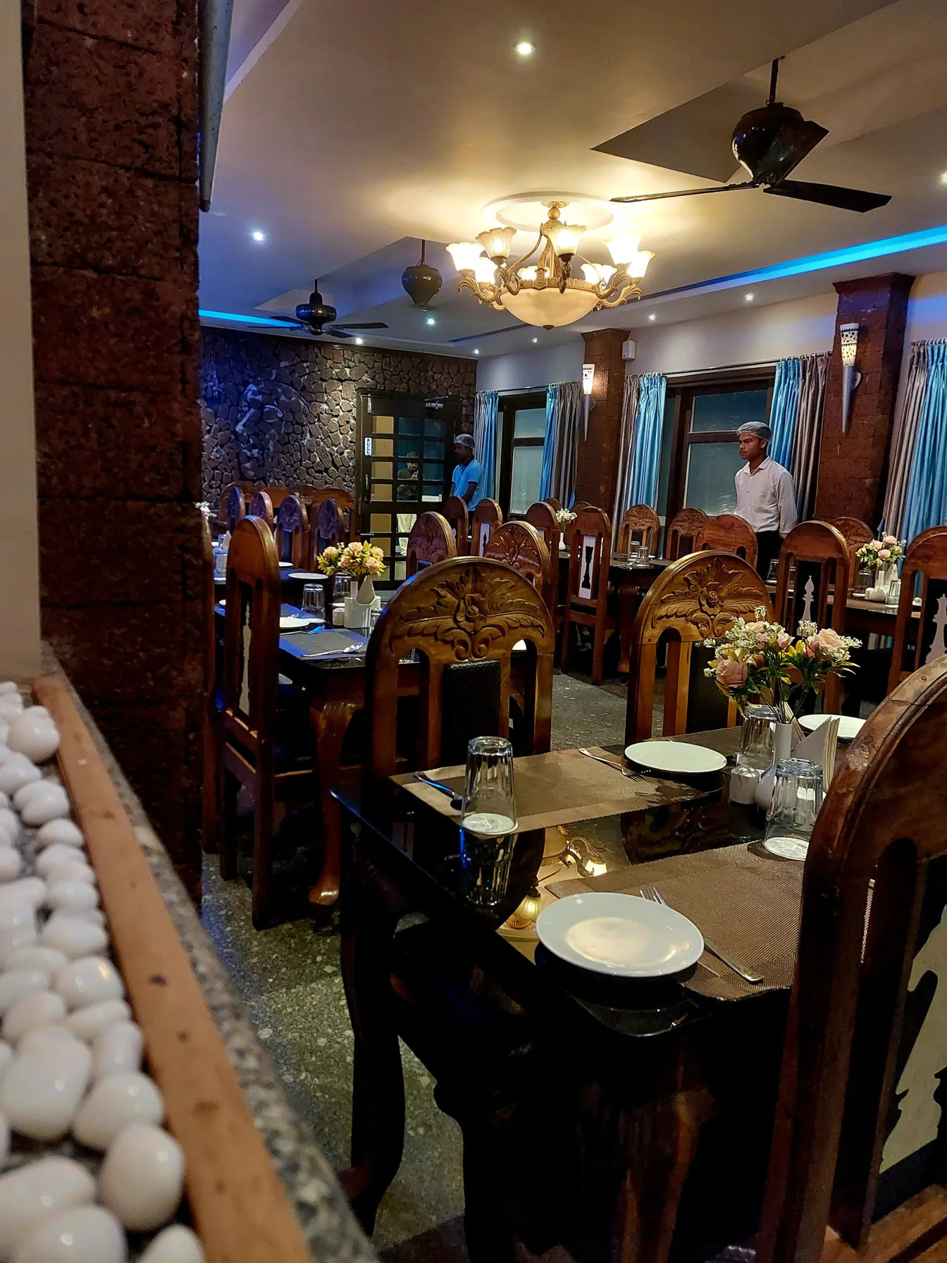 Byanjan dining room in daylight, wooden chairs and a glass table in front