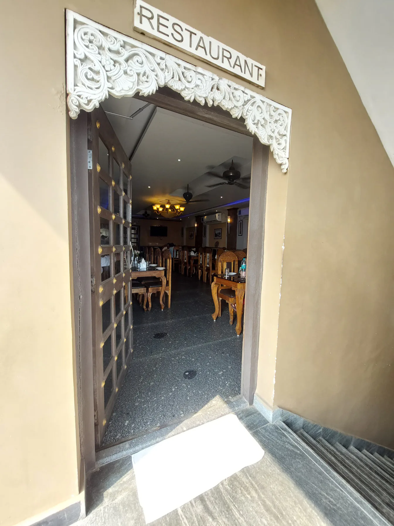 The restaurant entrance at Byanjan, a carved doorway under a wooden Restaurant sign