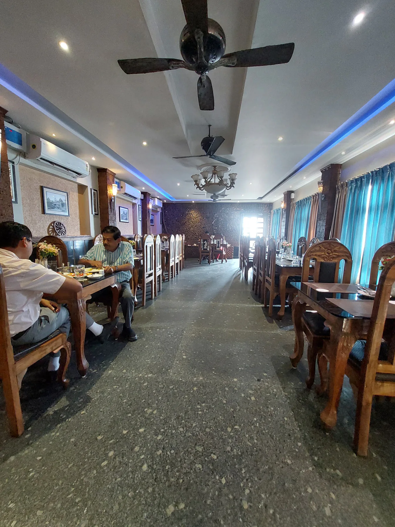 Guests at a table in the Byanjan dining hall, seen down the aisle