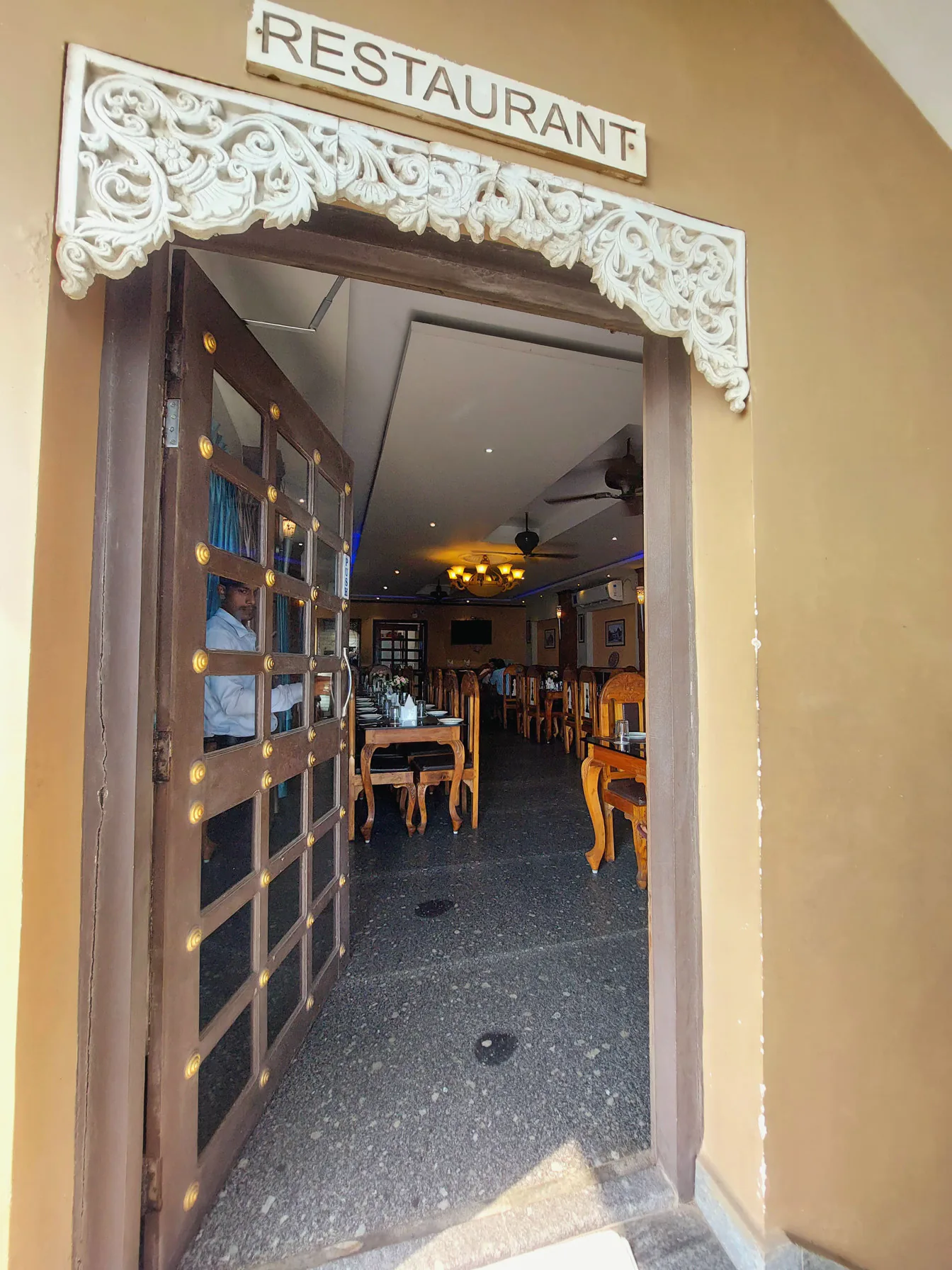 A staff member holding open the restaurant door at Byanjan